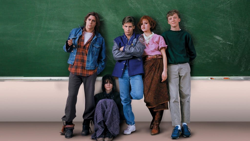 Personajes principales de El club de los cinco posando frente a un tablero verde en la escuela.