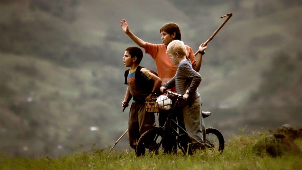 Tres niños en el campo colombiano, con una bicicleta, en una escena de Los colores de la montaña.