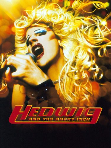 Hedwig en escena con peluca rubia y micrófono