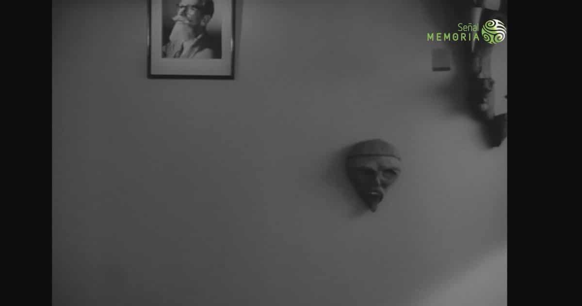 Pared interior con un retrato enmarcado y dos máscaras, en una escena en blanco y negro de La frontera del sueño