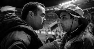Mariano Concha y Saúl, protagonistas de La pena máxima, se enfrentan en primer plano dentro de un estadio lleno, en una imagen en blanco y negro con ambiente de fútbol colombiano.