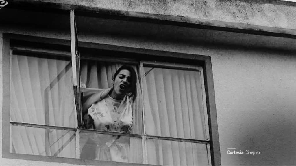 Sandra Reyes en La pena máxima, asomada por una ventana en blanco y negro, en una escena de tensión doméstica relacionada con Mariano Concha.