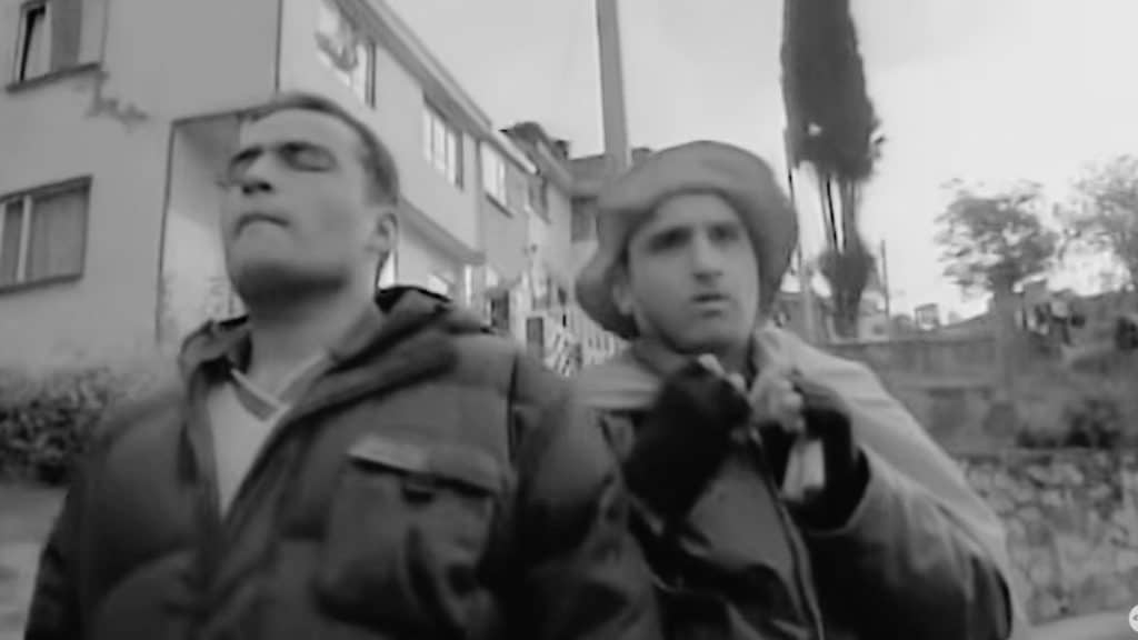 Mariano Concha y Saúl caminan por una calle de Bogotá en La pena máxima, en una escena en blanco y negro que muestra su carrera por llegar al partido de la Selección Colombia.