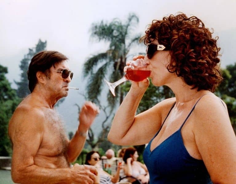 Escena de La Ciénaga, de Lucrecia Martel, con una mujer bebiendo una copa junto a un hombre que fuma al aire libre.
