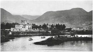 Fotografía antigua en blanco y negro del parque Luna Park en Bogotá, con laguna, botes y el edificio principal con torre reloj