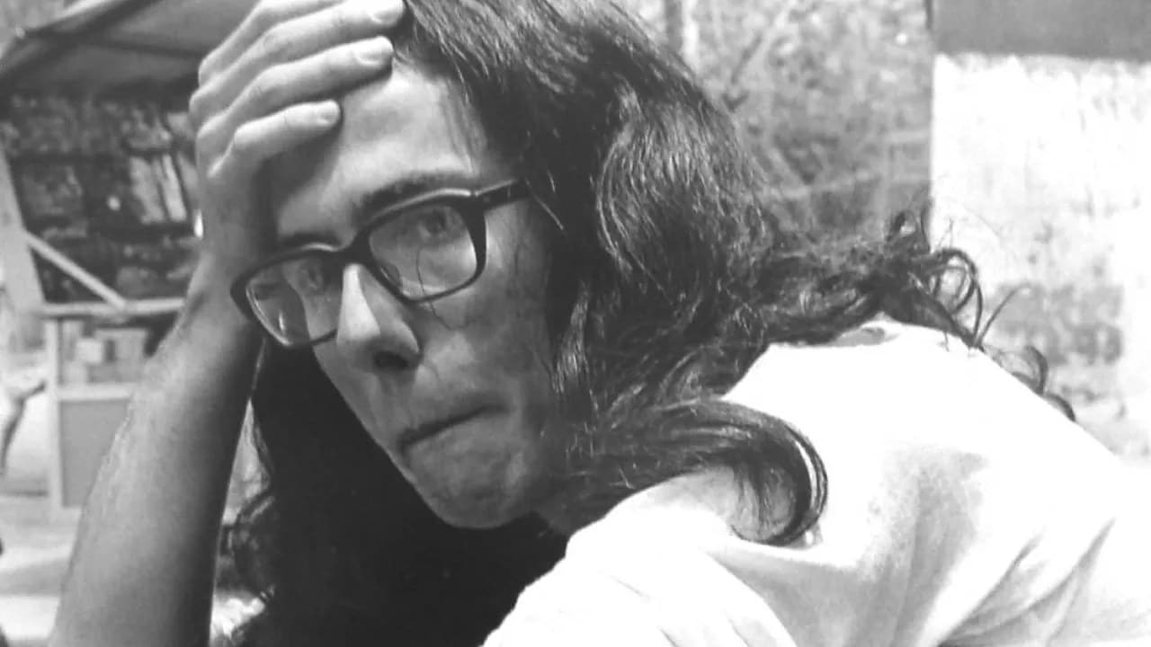 Andrés Caicedo en blanco y negro, con gafas y una mano sobre la frente, mira hacia un lado