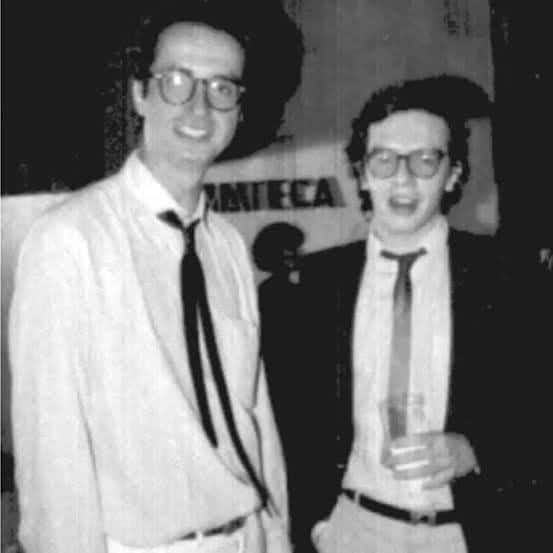 Fotografía en blanco y negro de Luis Ospina y Sandro Romero Rey, de pie y sonrientes, con corbata